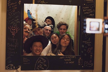 Man with friends around a photo booth.