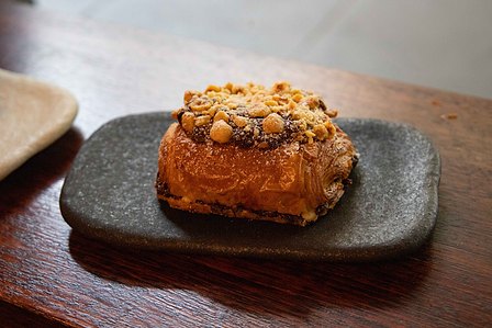Picture of a crisp chocolate croissant straight out of the oven sitting on black and white stone plate.