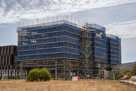 Clear blue skies with golden hay, green bushes, and scaffolding around the building.