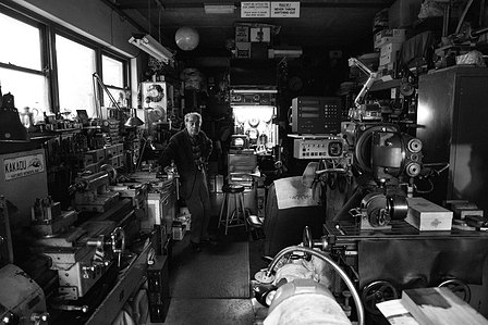 photo of an old engineer in his shed showing all of his machinery cameras and other various toys.