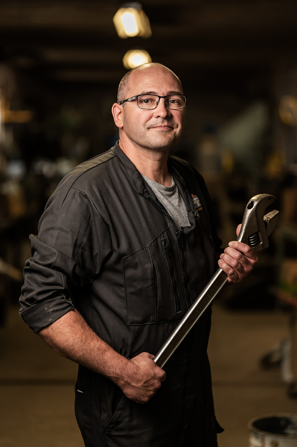 photographie portrait métier homme qui porte une clé à molette dans un atelier de mécanique Lyon  lotfi dakhli