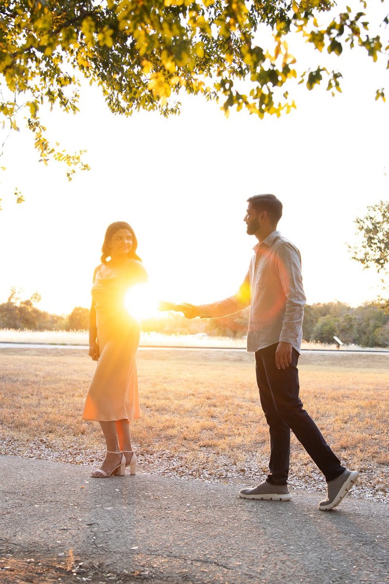 Expecting parents walking by the lake at sunset