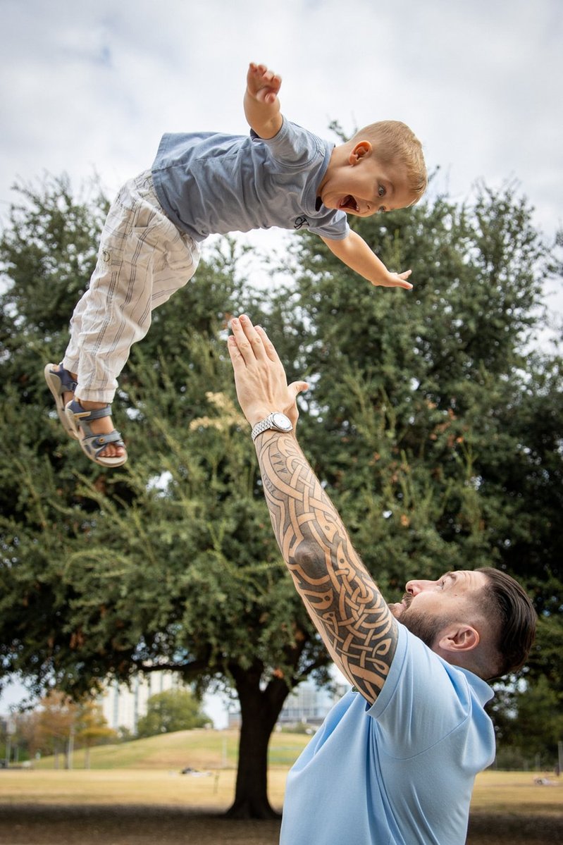 Father tossing child into the air in the park