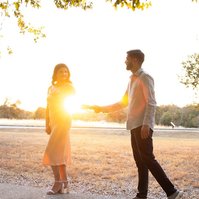 Expecting parents walking by the lake at sunset