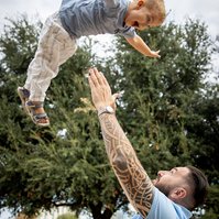 Father tossing child into the air in the park