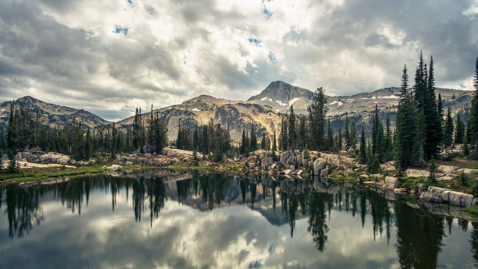 Storm clouds and mountain peaks reflecting in an alpine lake.