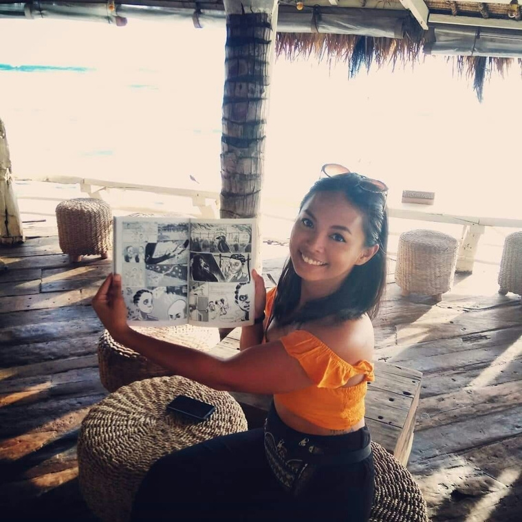 Asia Noble woman holding up a comic she drew in a beach bar in Bali