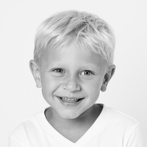 school age boy in white v neck shirt laughing and showing his missing teeth