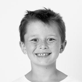 school aged boy in a white shirt with a big funny smile in black and white