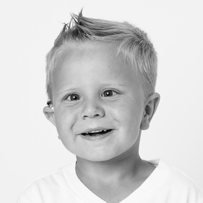 toddler boy with cochlear smiling a big smile in black and white 