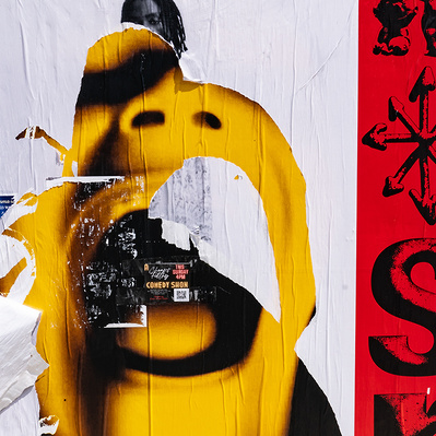 A giant, acid-yellow open mouth screaming or singing is what remains of a larger poster. The mouth appears from under a mostly white background with one partially obscured Black man hidden behind the mouth. A vertical red banner w/black letters frames all
