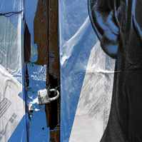 This image features a  segment from a wall of posters and a locked door with a Master lock. The poster is of the side of a Black Man's head, with only one ear showing next to the lock. The highlights on the ear are in blue, reflecting the layered image. 