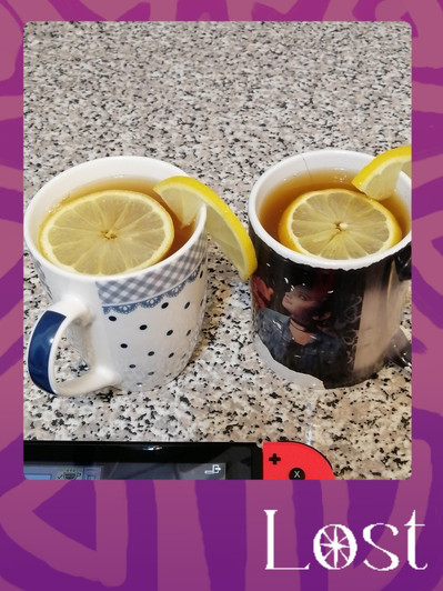 Gallery Image: Text reads: LOST. On a purple border around an image of two cups of lemon hot tea in mugs with slices of lemon floating on top. At the bottom of image a Nintendo switch is partially visible.