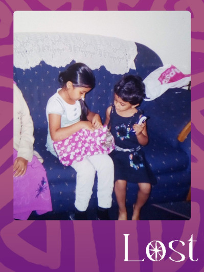 Gallery Image: Text reads: LOST. On a purple border around an image of two young girls sitting on a couch opening a present box covered in pink and white wrapping paper.