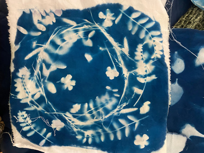 Gallery Image: blue cyanotype print on white fabric: print of a circle made of vines, leaves and flowers.