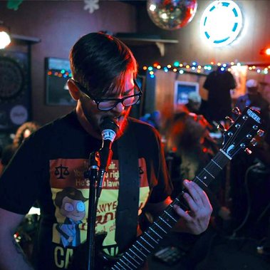 man singing into mic and playing guitar
