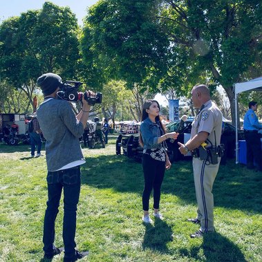 man filming lady with microphone interviewing police officer