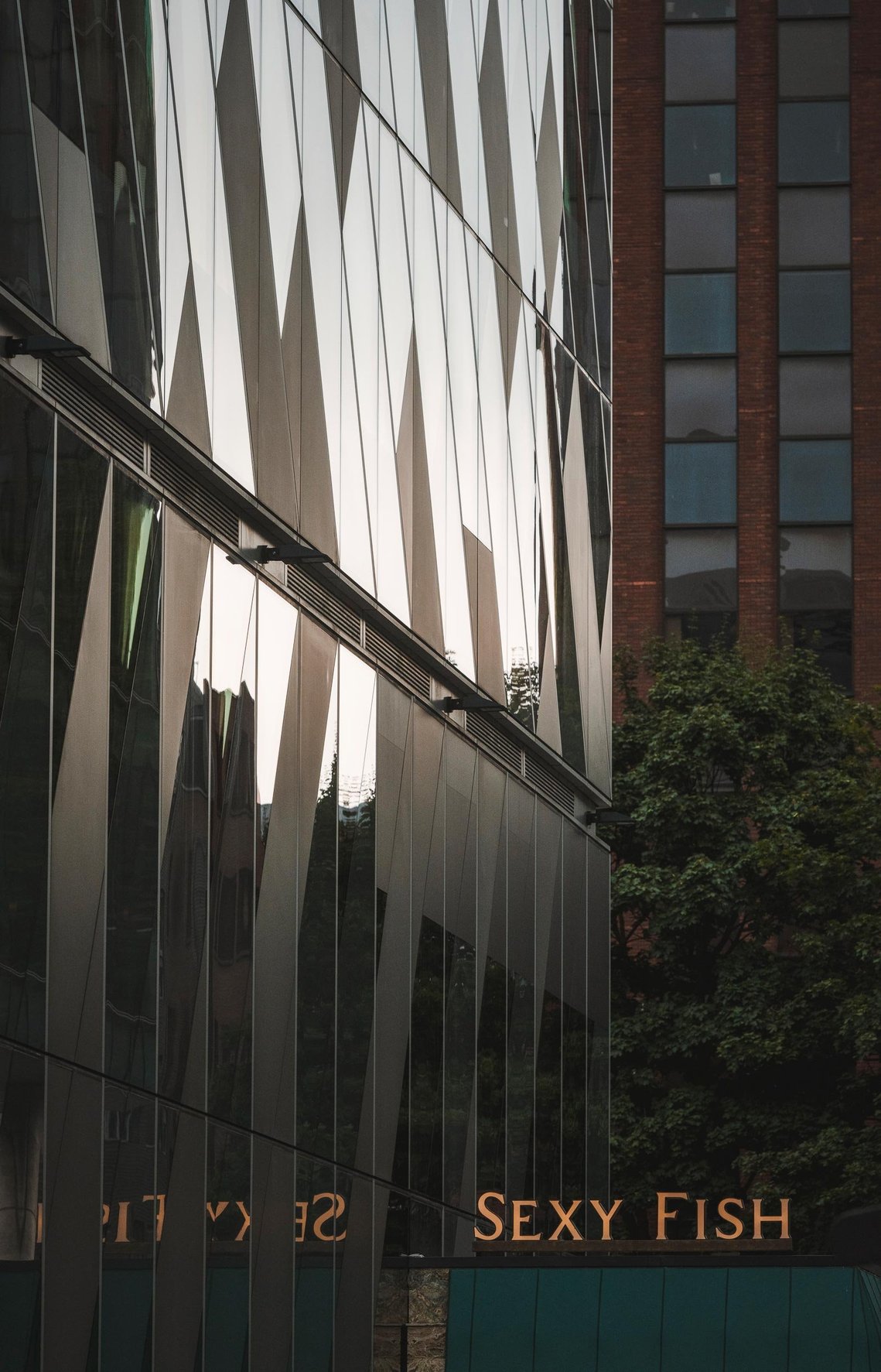 URBAN LIFESTYLE AND LOCAL AREA PHOTOGRAPHY OF SPINNINGFIELDS, MANCHESTER, shot of glass building in evening light and signage for restaurant 