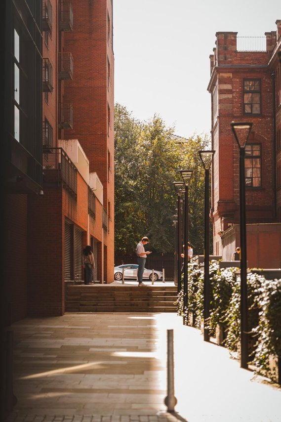 URBAN LIFESTYLE AND LOCAL AREA PHOTOGRAPHY OF SPINNINGFIELDS, MANCHESTER, lifestyle photography showing person on phone with tall buildings and steps
