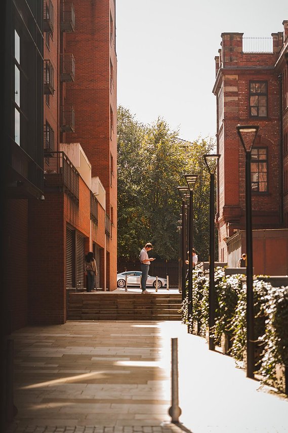 URBAN LIFESTYLE AND LOCAL AREA PHOTOGRAPHY OF SPINNINGFIELDS, MANCHESTER, lifestyle photography showing person on phone with tall buildings and steps
