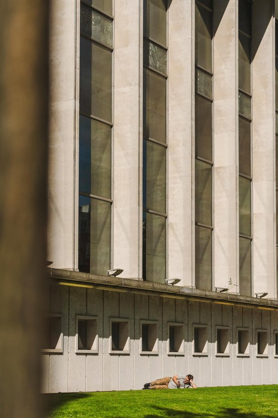 URBAN LIFESTYLE AND LOCAL AREA PHOTOGRAPHY OF SPINNINGFIELDS, MANCHESTER, lifestyle photograph showing worker relaxing on grass outside building in sunshine 