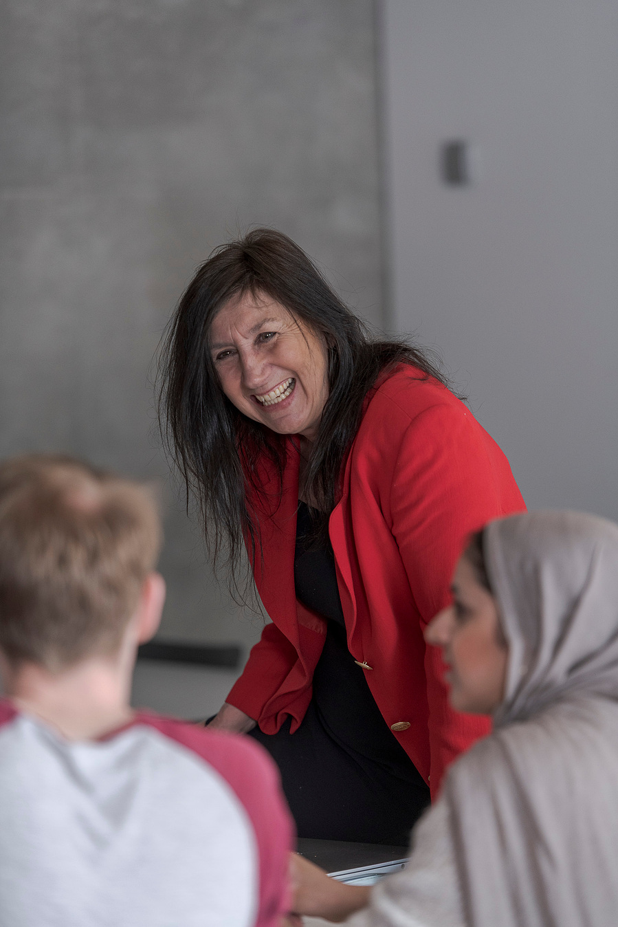 student lifestyle photography and education photography, class environment, collaborative working between group of students, focus on tutors sat on desk and smiling as she discusses work with students