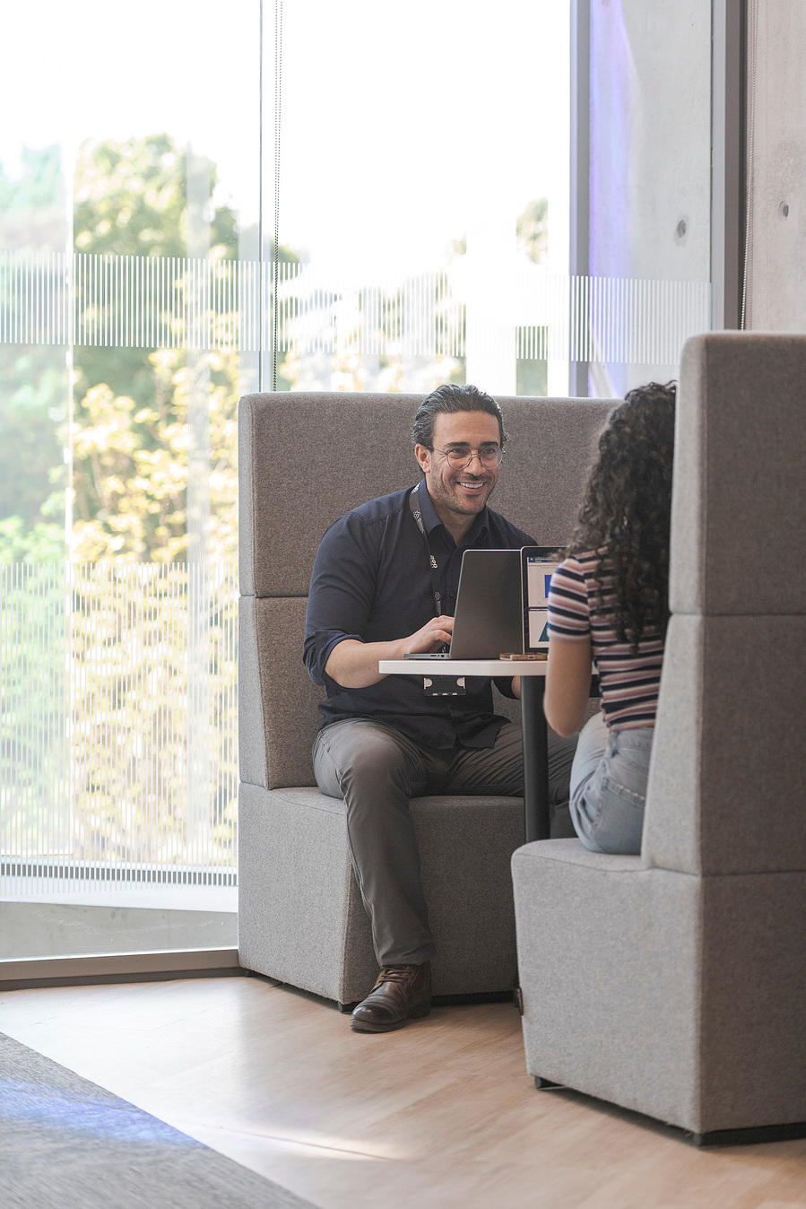 student lifestyle photography and education photography, class environment, discussion between and tutor and student in a booth with large window behind