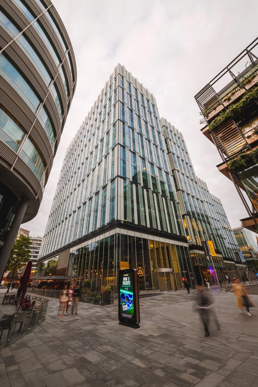 URBAN LIFESTYLE AND LOCAL AREA PHOTOGRAPHY OF SPINNINGFIELDS, MANCHESTER. view of high rise building and blurred walkers in foreground