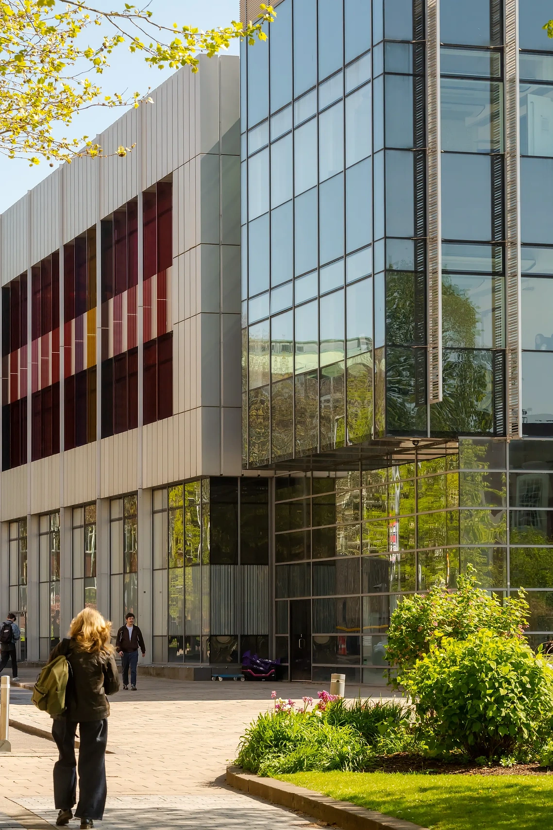 Modern glass architectural structure with people and greenery