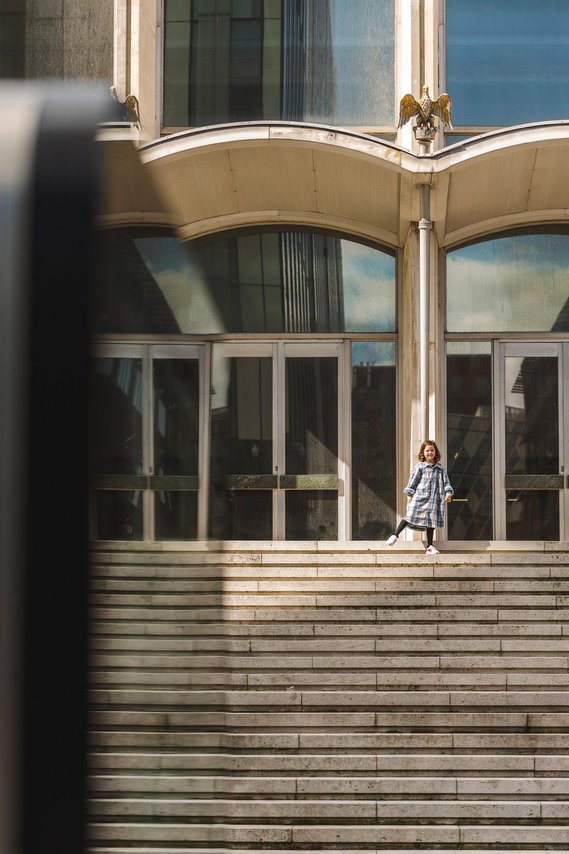 URBAN LIFESTYLE AND LOCAL AREA PHOTOGRAPHY OF SPINNINGFIELDS, MANCHESTER, lifestyle photography showing a small child playing on the steps in front of a building sunshine 