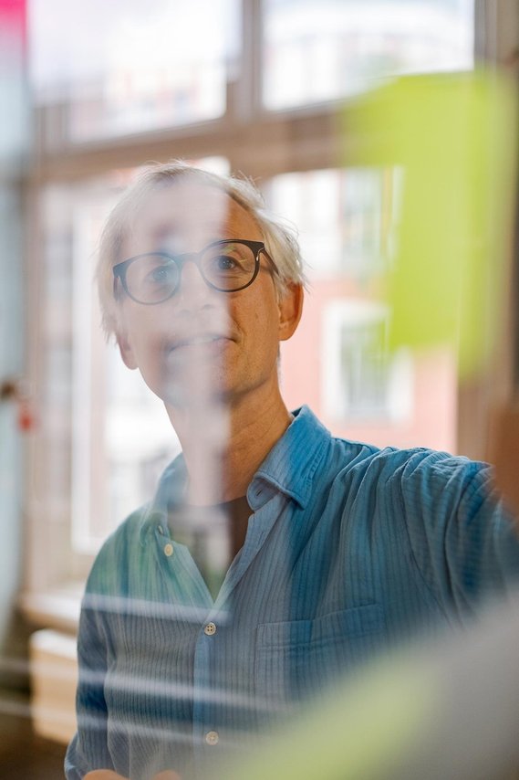 commercial lifestyle photography, person looking toward camera sticking notes on glass wall