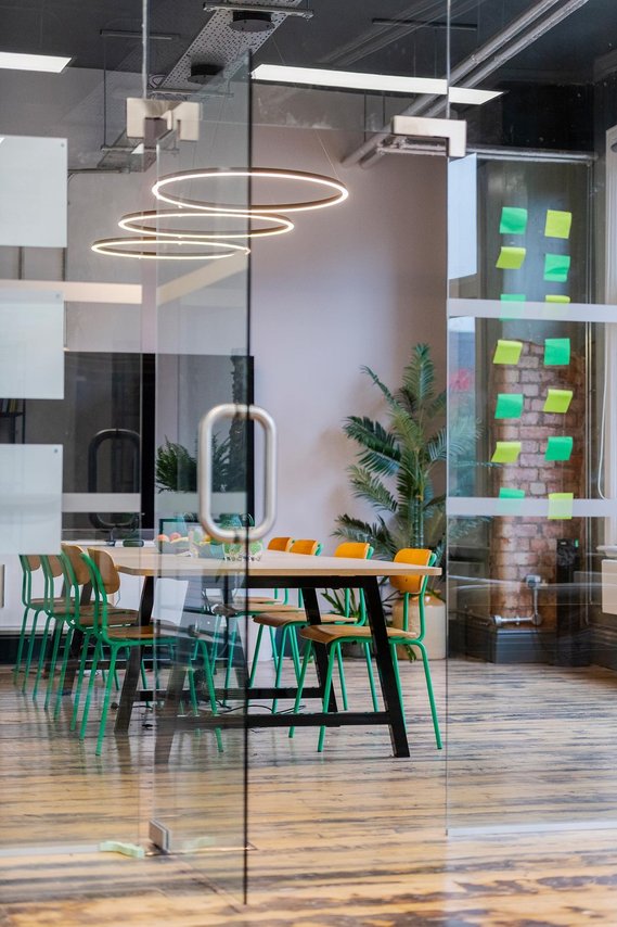 empty meeting room in workplace, interior photography shows table and chairs with notes stuck on glass wall.