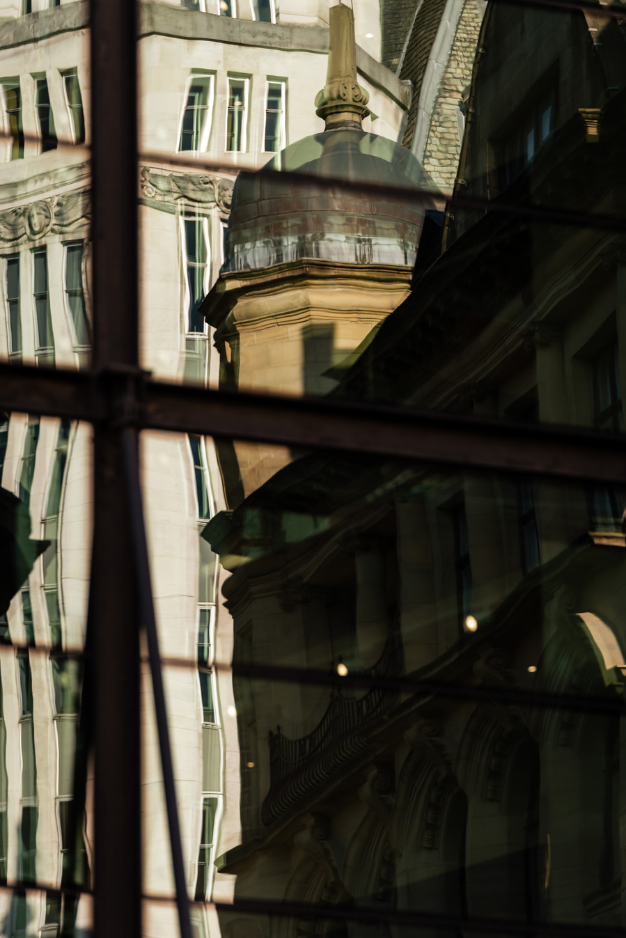 Abstract city photography showing manchester buildings reflected in glass of another building. image appears warped by the reflections.