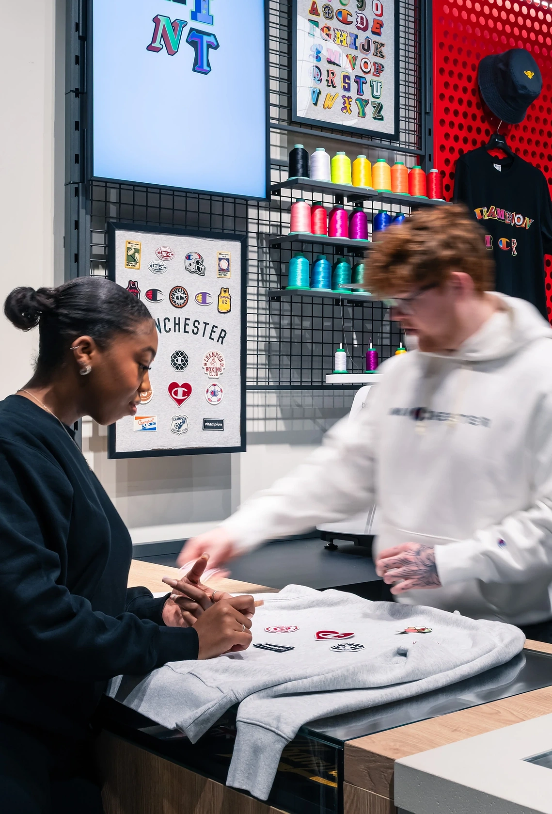 Commercial lifestyle photograph of the customisation station feature area in a Manchester retail space with staff.