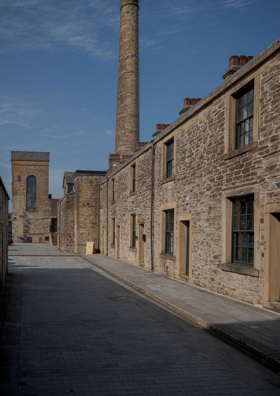  Exterior of Root Fifty-Two's office in Burnley, showing a row of stone terraced buildings. A signboard at the entrance reads 'We Elevate Brands,' highlighting the agency’s historic and inviting location.
