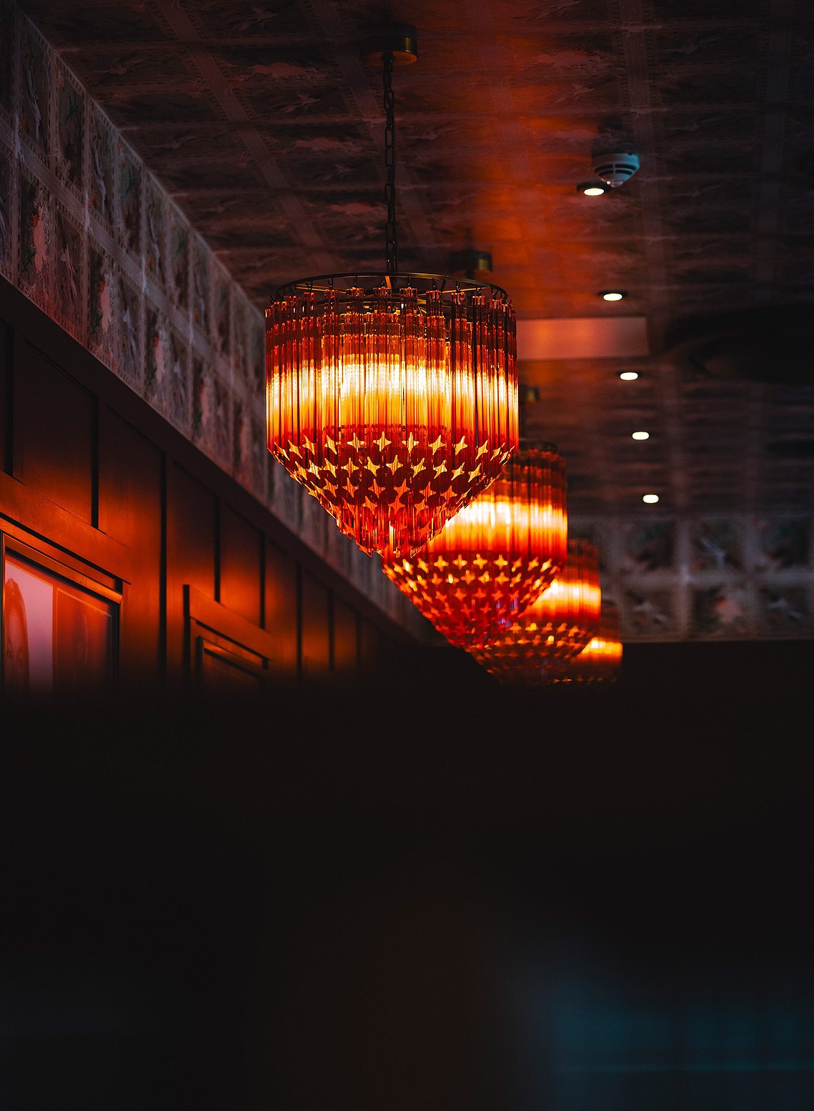 interior photography showing ornate ceiling lights glowing red in a cinema lobby
