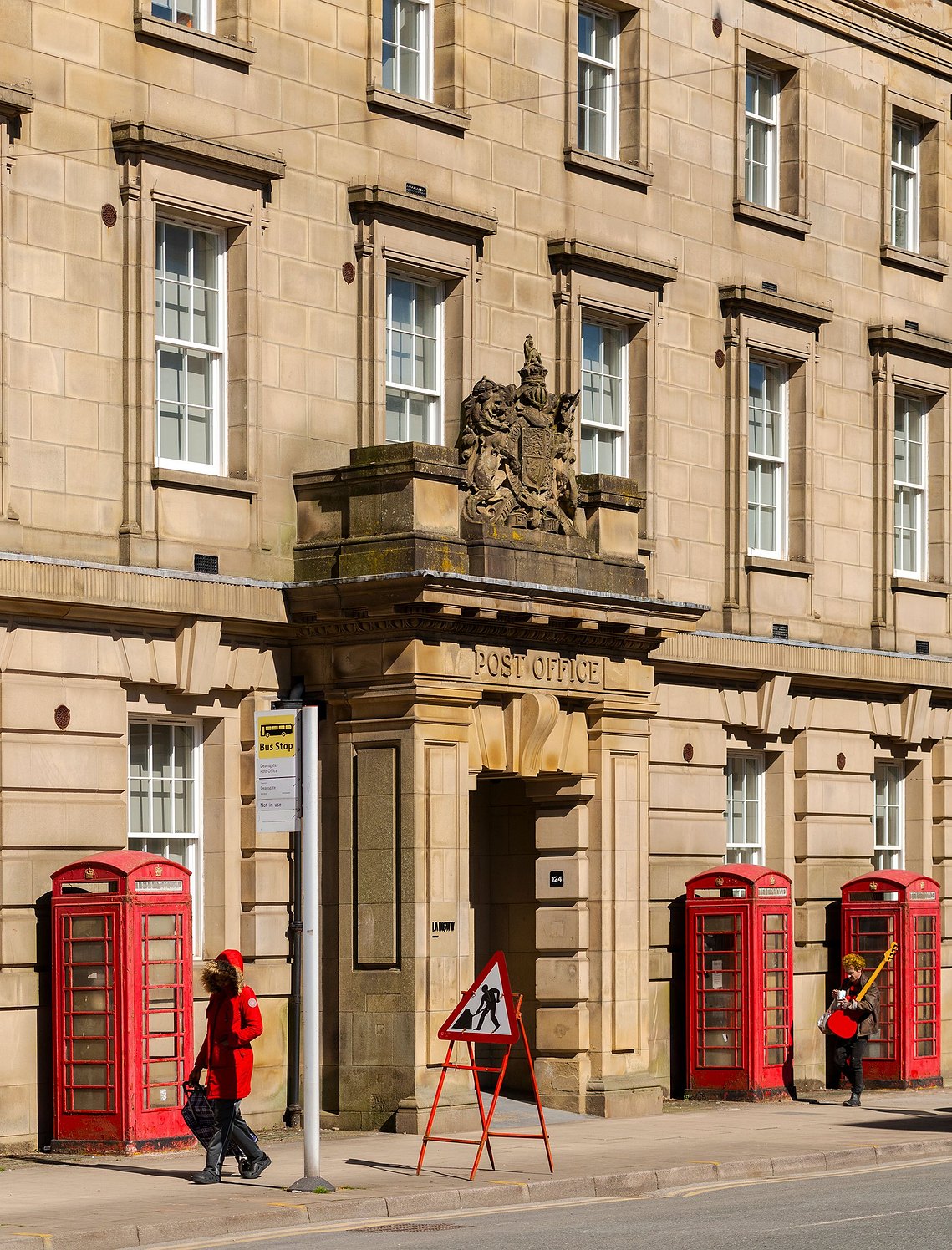 architecture and lifestyle photography, manchester street photography, people all wearing red walk past municipal building in manchester borough