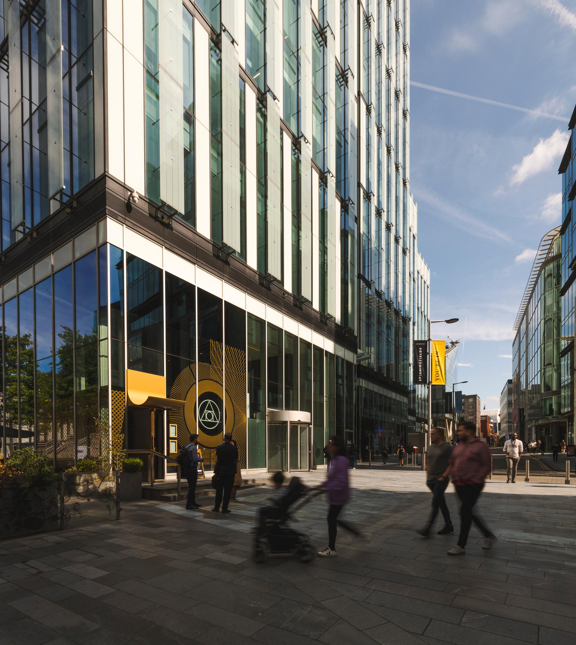 URBAN LIFESTYLE AND LOCAL AREA PHOTOGRAPHY OF SPINNINGFIELDS, MANCHESTER, street scene showing high rise glass buildings, blue skies and people walking in the foreground 