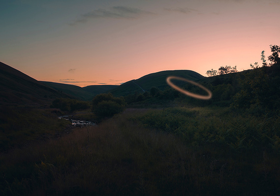 twilight landscape, countryside, hills in background and sun setting behind. mysterious ring of light hovers in foreground
