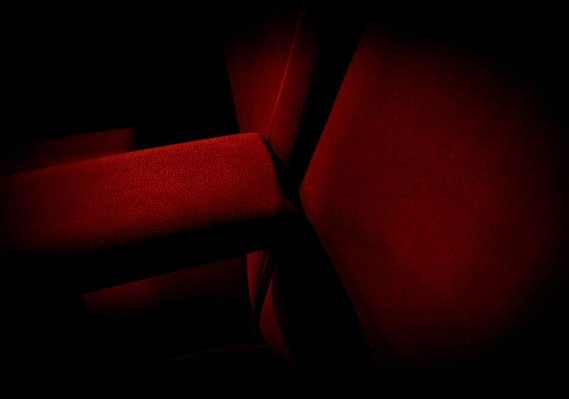 abstract photograph of cinema seats. red velvet texture and dramatic lighting