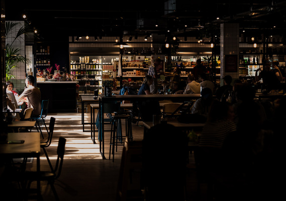 Interior of food place. long tables. dark lighting but bright sunlight from windows. 