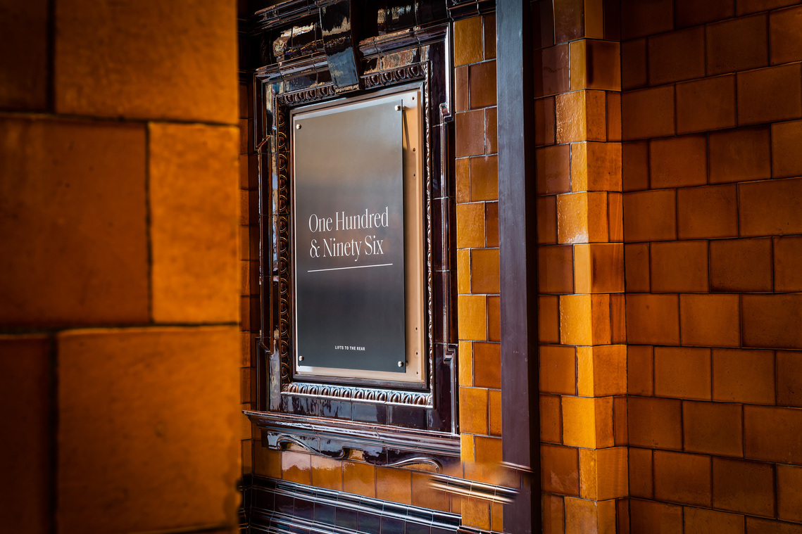 Property interior photography that shows the original orange period tiled walls in an entrance area. A sign displays the building name.