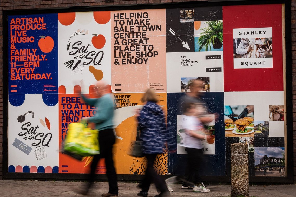 blurred shoppers walk past advertising posters, placemaking and lifestyle photography