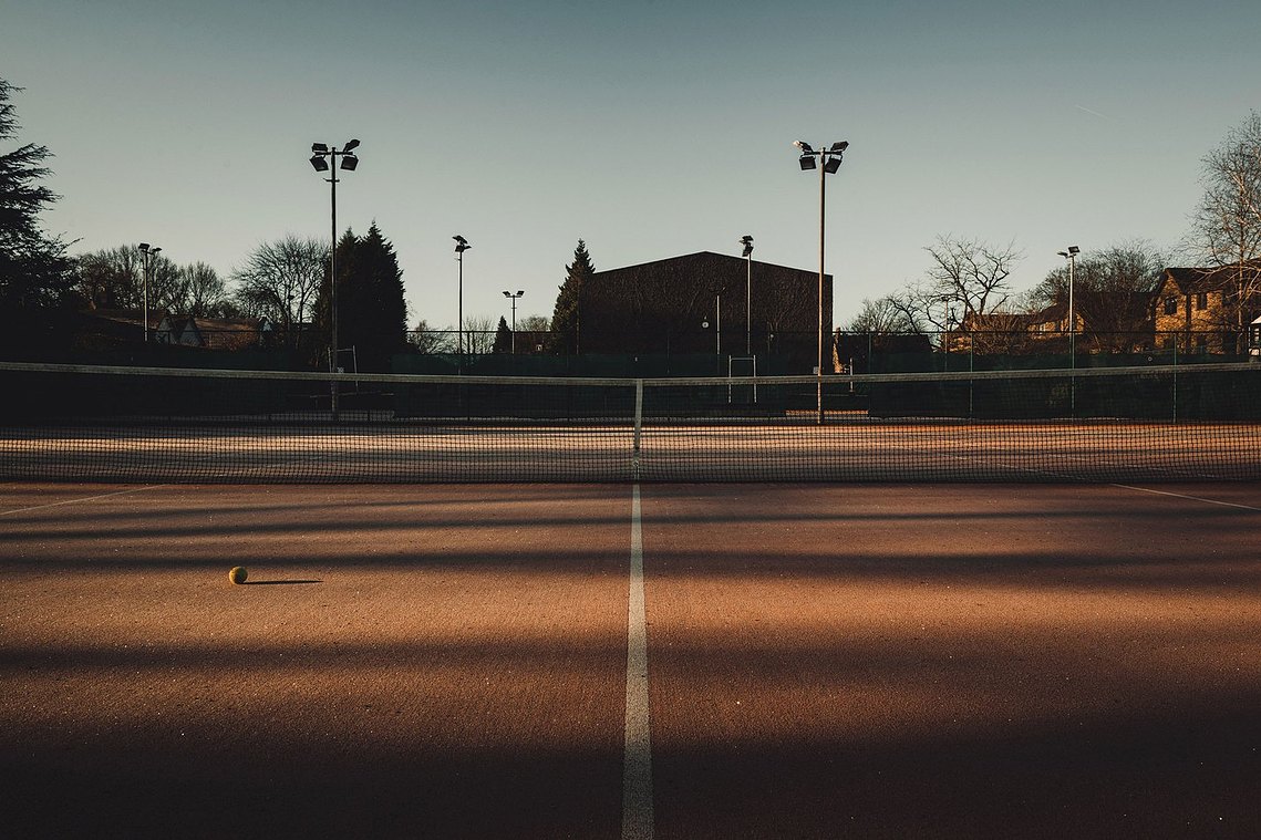 empty tennis court, evening light, tennis ball on floor, shadows