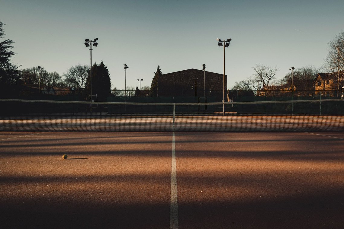 empty tennis court, evening light, tennis ball on floor, shadows