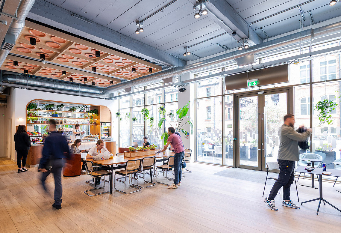 Manchester freelance photographer documenting modern office lifestyle. Wide shot of communal area with benches and cafe