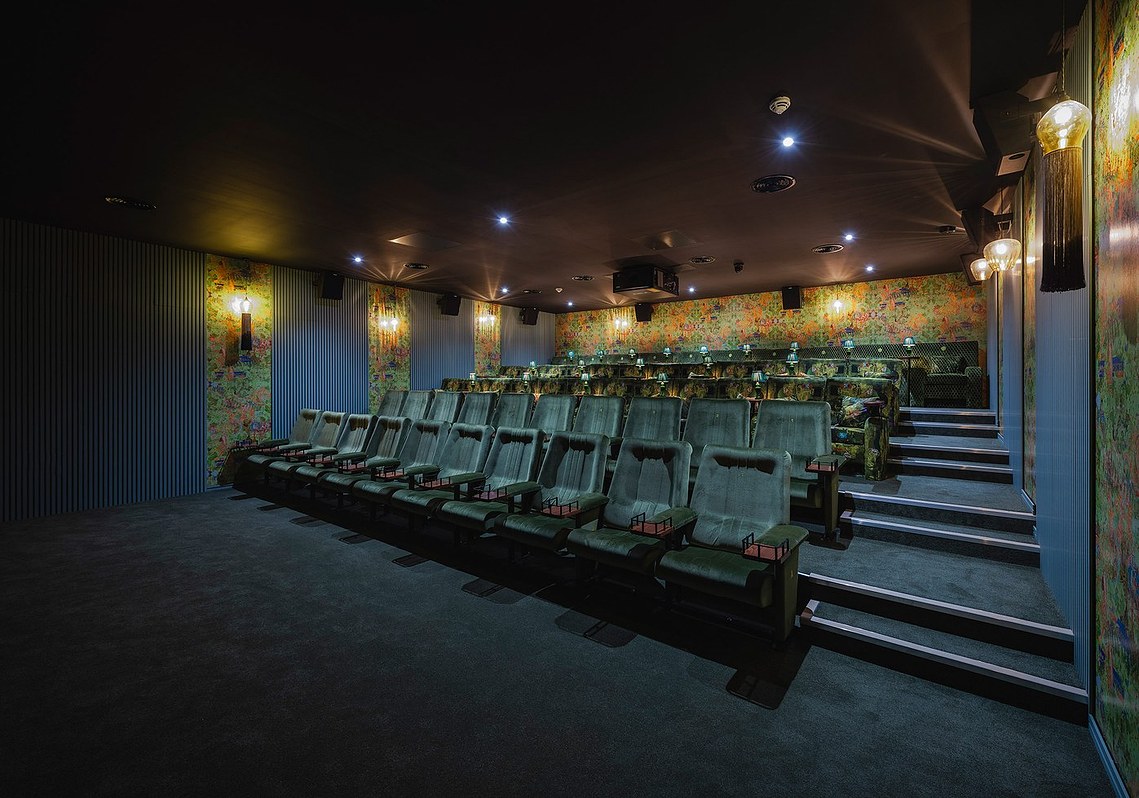 interior photography of cinema interior, auditorium with view of rows of seats, blue and green decoration and boutique lamps