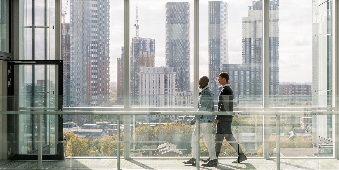 Commercial lifestyle photography showing workers in glass building with city scape in background