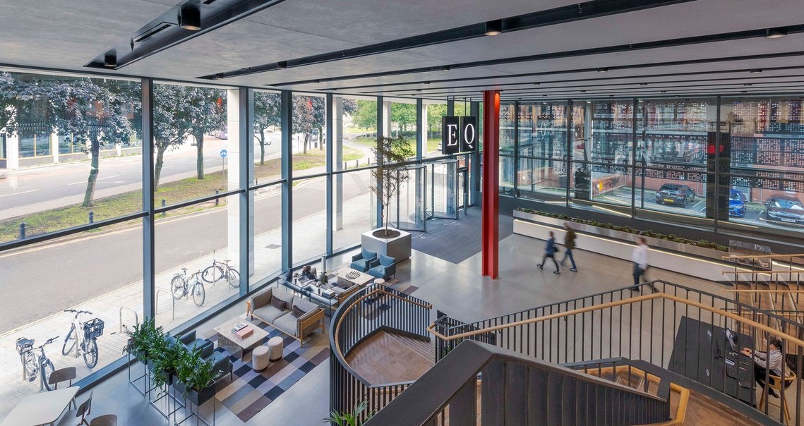 architecture photography of vast interior reception space in modern building with people walking through the frame and architectural staircase in foreground