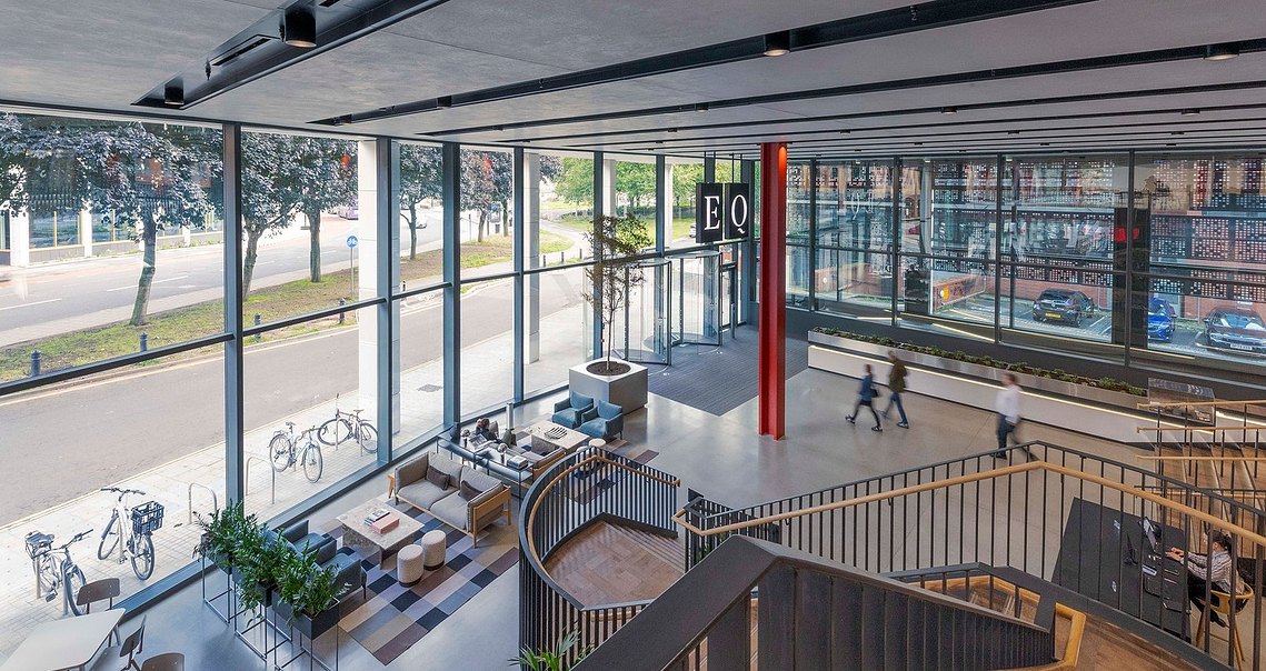 architecture photography of vast interior reception space in modern building with people walking through the frame and architectural staircase in foreground